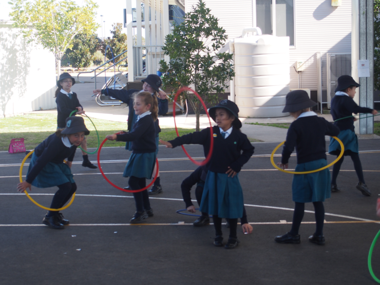 Here are some girls dancing using with a hola hoop.