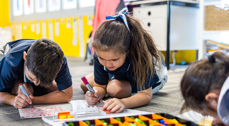 Students writing together on the floor at Our Lady of the Angels Primary School Rouse Hill