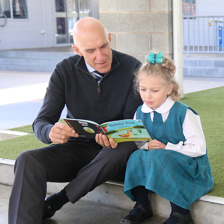 Principal Tony Calabria reading with a student at Our Lady of the Angels Primary School Rouse Hill